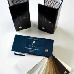 Prezentacja palety kolorów profili aluminiowych firmy FINAL, z otwartymi pudełkami wizytówek w tle, na białym tle.