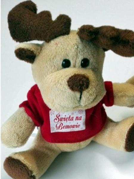 Pluszowy renifer w czerwonej koszulce z napisem 'Święta na Bemowie' na białym tle.