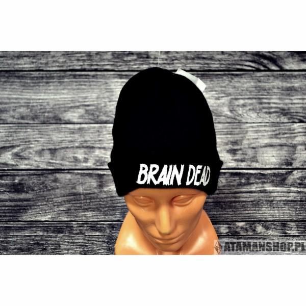 Czarna czapka typu beanie z białym napisem 'BRAIN DEAD' na manekinie z tworzywa sztucznego na tle z desek.