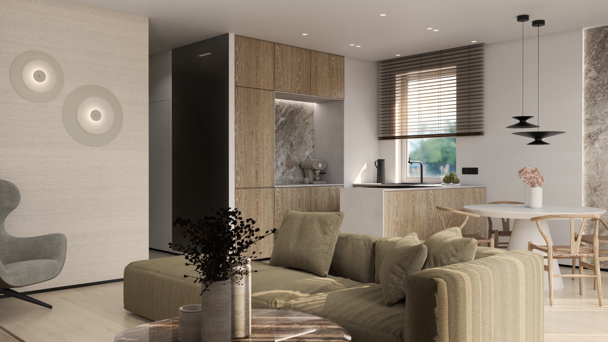 Jasne wnętrze z drewnianą zabudową kuchenną, okrągłym stołem i sofą w odcieniach beżu. Minimalistyczne lampy na ścianie i designerskie oświetlenie nad stołem.