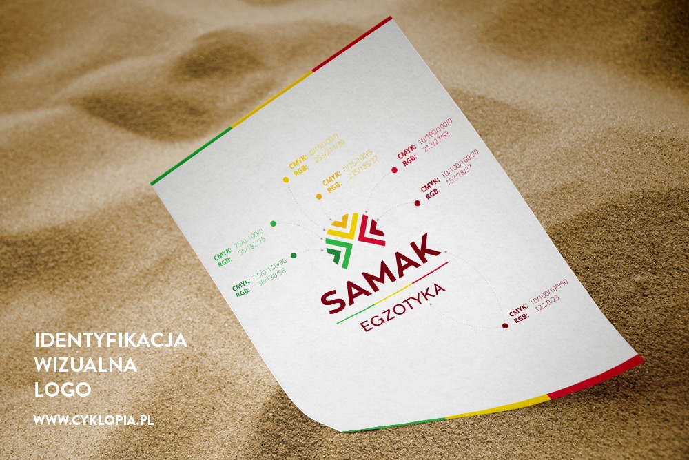 Prezentacja logo 'Samak Egzotyka' na białej kartce z kolorowymi oznaczeniami CMYK i RGB, ułożonej na tle piasku.