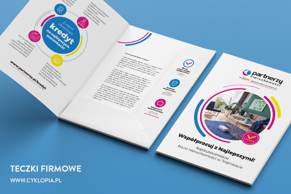 Otwarta teczka firmowa z materiałami reklamowymi, prezentująca ofertę kredytową i usługi biura nieruchomości, na jasnoniebieskim tle.