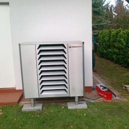 COP Łódź Beata Latkowska - Zewnętrzna jednostka pompy ciepła marki Mecaterm ustawiona na betonowych podstawach obok budynku z białymi drzwiami, z widoczną skrzynką narzędziową firmy Rothenberger w tle.