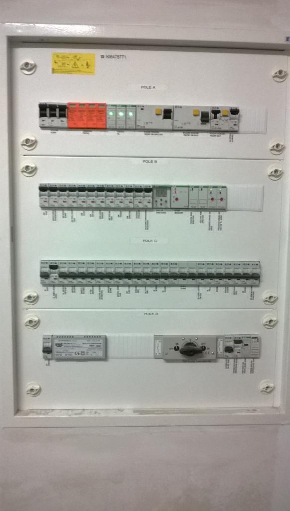 Rozdzielnica elektryczna z czterema rzędami zabezpieczeń oznaczonych jako POLE A, B, C, D, zawierająca wyłączniki nadprądowe, różnicowoprądowe i selektor obrotowy, zamontowana w białej obudowie...