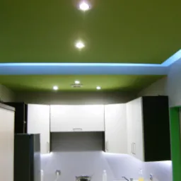 Kuchnia po remoncie z zielonym sufitem podwieszanym z oświetleniem LED, białe szafki wiszące z czarnymi elementami, widoczne naczynia na blacie.