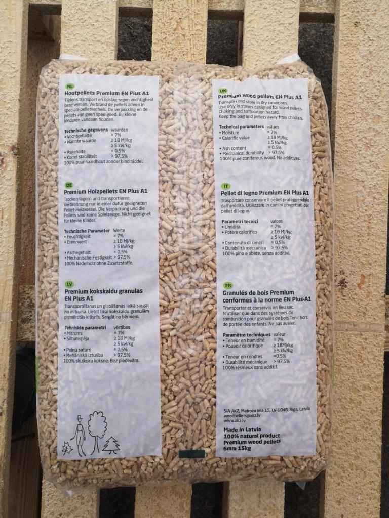 Worek pelletu drzewnego EN Plus A1, 15kg, wyprodukowany na Łotwie. Opis w kilku językach, widoczne parametry techniczne. Naturalny produkt z drewna iglastego.