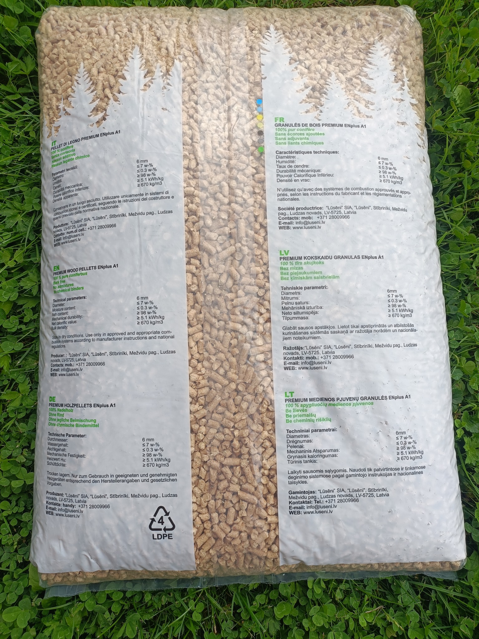 Worek pelletu drzewnego ENplus A1, z opisem parametrów w kilku językach, leżący na trawie. Widoczne logo LDPE i informacje o producencie.