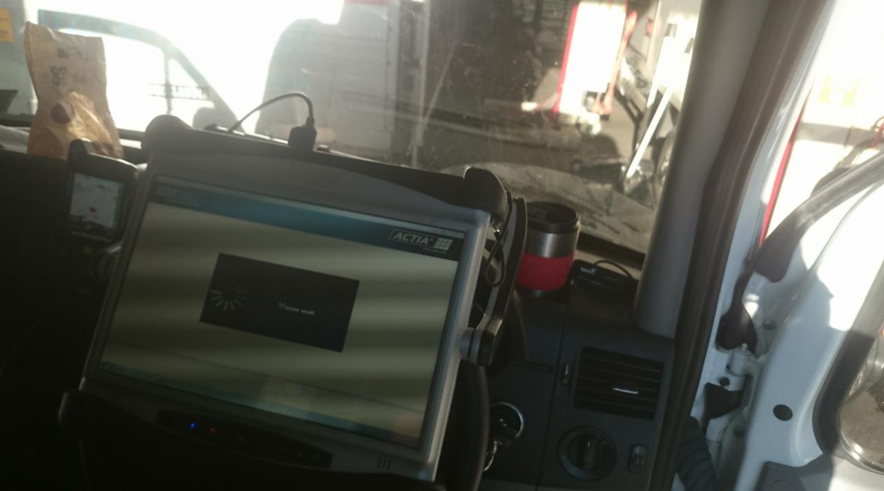 Ekran diagnostyczny ACTIA w kabinie pojazdu, w tle widoczne inne pojazdy, prawdopodobnie podczas serwisu w terenie.