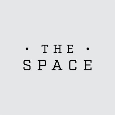 Minimalistyczne logo 'The Space' z dwoma kropkami po bokach, czcionka bezszeryfowa na jasnoszarym tle.