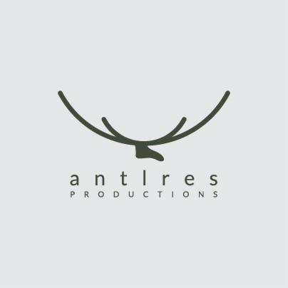 Minimalistyczne logo firmy 'antlres productions' przedstawiające stylizowane poroże jelenia w kolorze ciemnej zieleni na jasnoszarym tle.