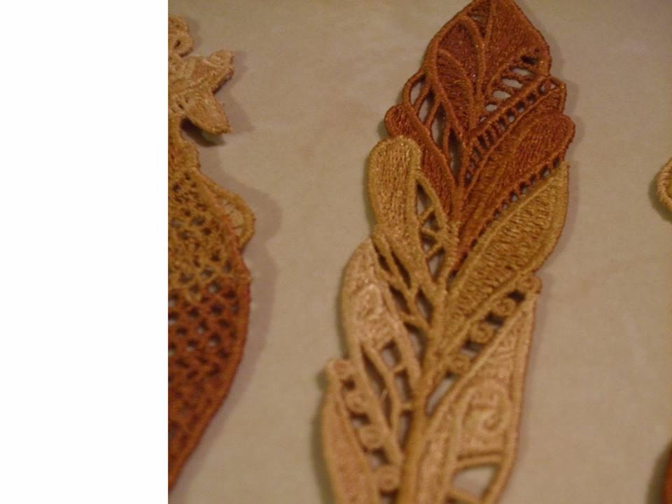 Brązowo-beżowe, ażurowe aplikacje z nici w kształcie liści, widoczne detale ściegów i wzorów.