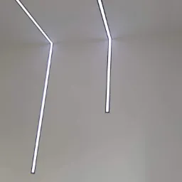 Nowoczesne oświetlenie sufitowe z liniowymi lampami LED w minimalistycznym wnętrzu, tworzące geometryczny wzór.