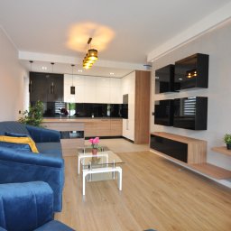 Rentsell Cengiz Yurekli - Jasne wnętrze salonu z aneksem kuchennym, ściana wykończona gładzią, podłoga z paneli drewnopodobnych, nowoczesne meble.