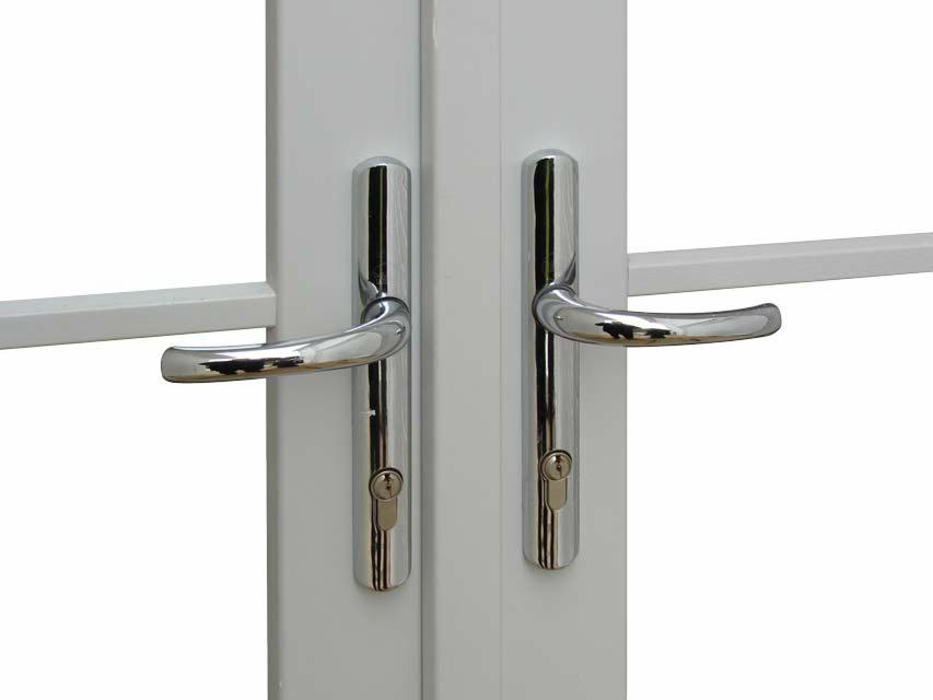 Białe drzwi balkonowe z chromowanymi klamkami i zamkami, detale stolarki okiennej z Krotoszyn. Widoczne skrzydła okienne z poprzeczkami.