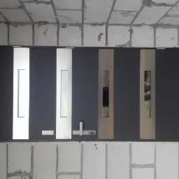 Montaż wieloskrzydłowych, nowoczesnych drzwi zewnętrznych z przeszkleniami, widoczne surowe ściany z betonu komórkowego i ocieplenie w szczelinach.