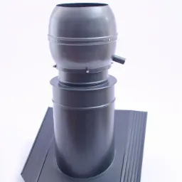 Szary kominek wentylacyjny z metalową podstawą na białym tle, widoczne nity i rurka odprowadzająca.