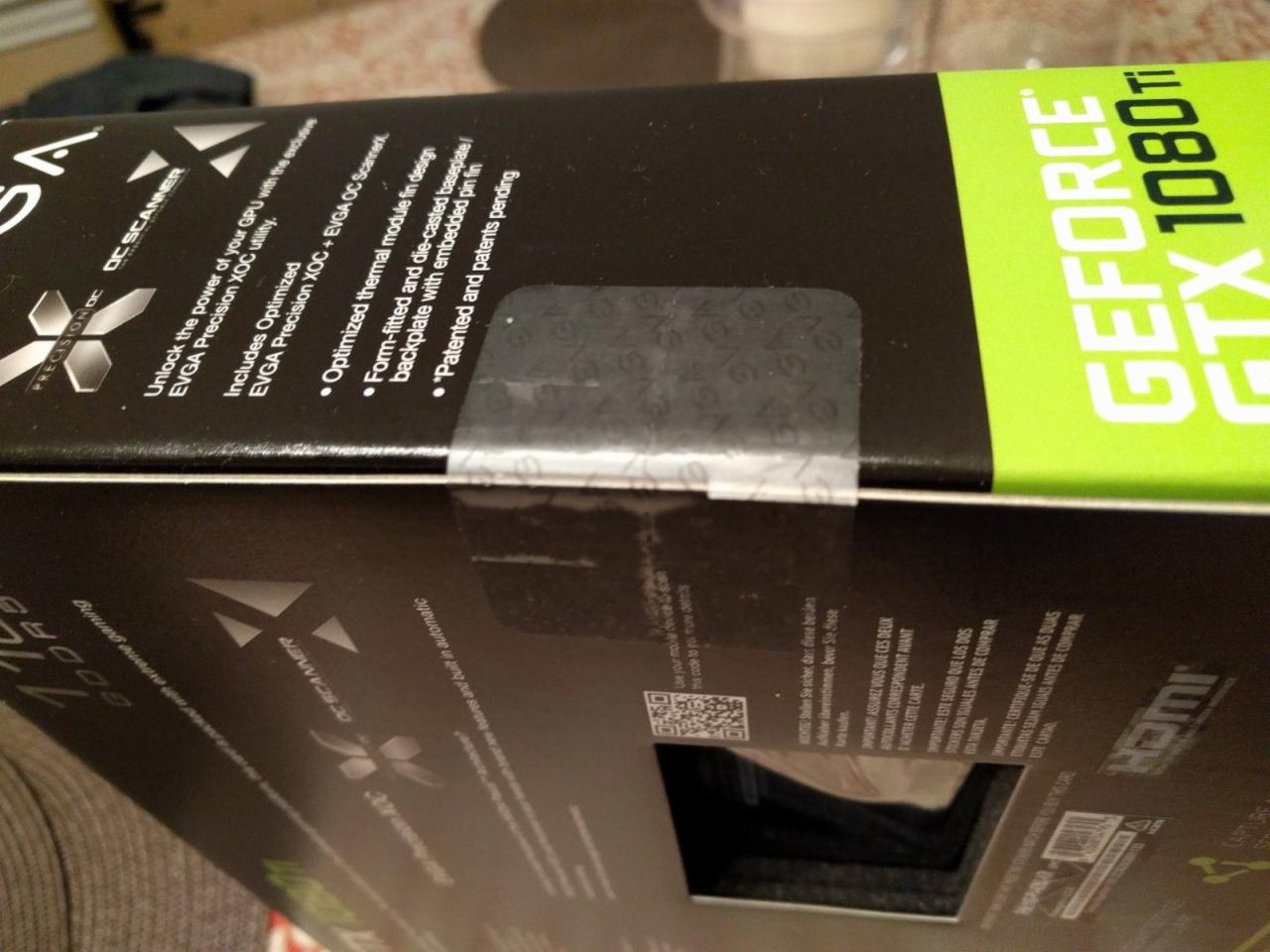 Pudełko karty graficznej GeForce GTX 1080 Ti, z widocznym hologramem zabezpieczającym i informacjami o specyfikacji produktu.