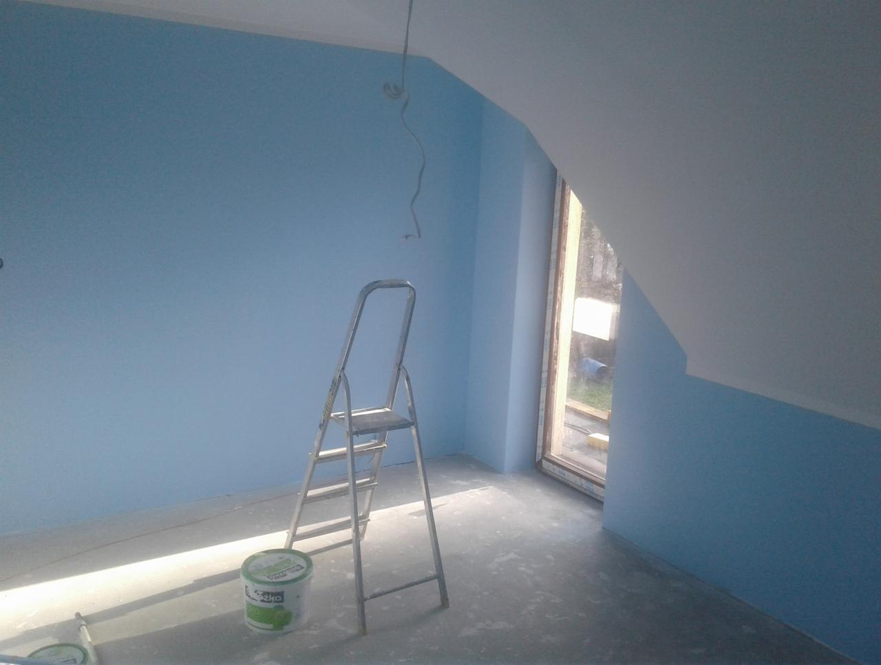 Świeżo pomalowane na błękitno poddasze ze skosami, z metalową drabiną i wiadrem farby na podłodze, widoczne przewody elektryczne zwisające z sufitu.