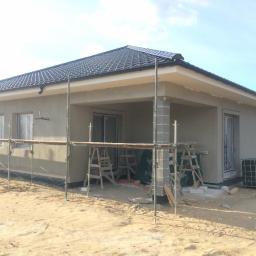 Finestre Okna Sp. z o.o. - Dom jednorodzinny w trakcie tynkowania zewnętrznego, widoczne rusztowania i niezabezpieczone okna.