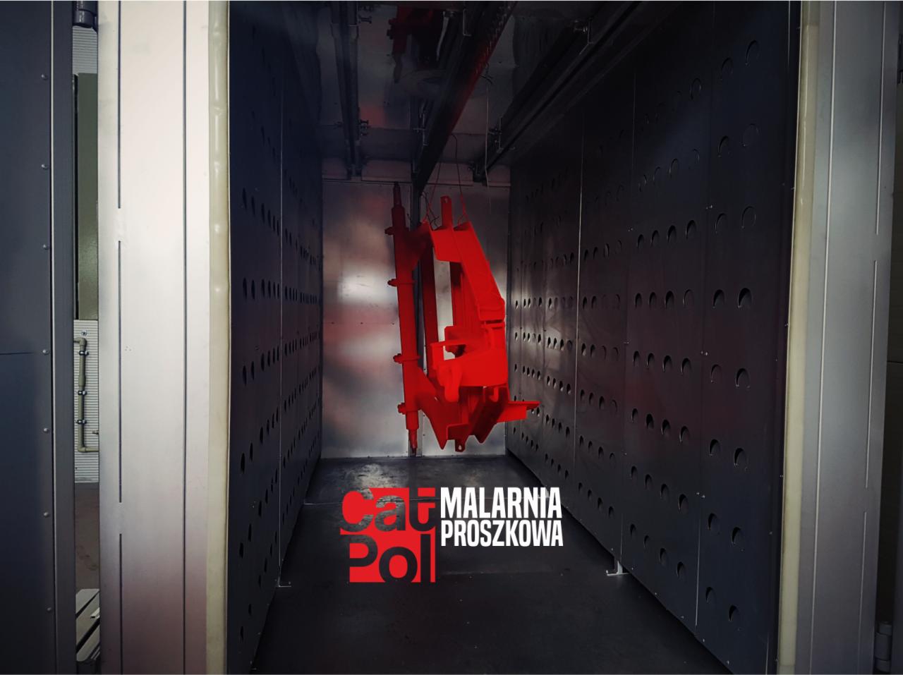Czerwony element konstrukcyjny zawieszony wewnątrz pieca do malowania proszkowego, widoczne perforowane ściany i logo firmy Malarnia Proszkowa.