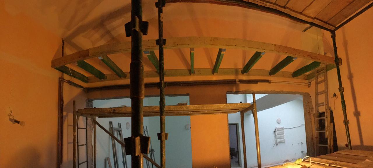 Wnętrze w Dębicy w trakcie remontu: widoczne rusztowania, drewniana konstrukcja sufitu podwieszanego oraz przygotowane otwory w ścianach.