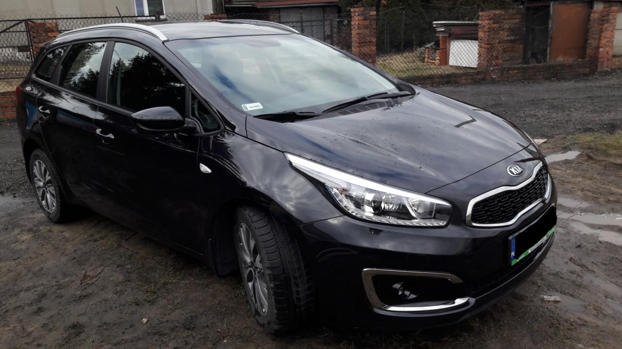 Czarny samochód typu kombi marki Kia zaparkowany na błotnistym podłożu, widoczne detale karoserii i opon.