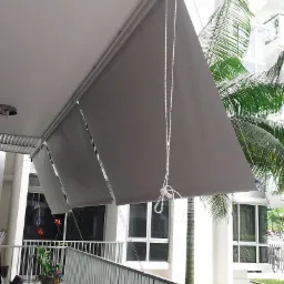 Zewnętrzne osłony przeciwsłoneczne w kolorze szarym, zamontowane na balkonie z widokiem na tropikalną roślinność.