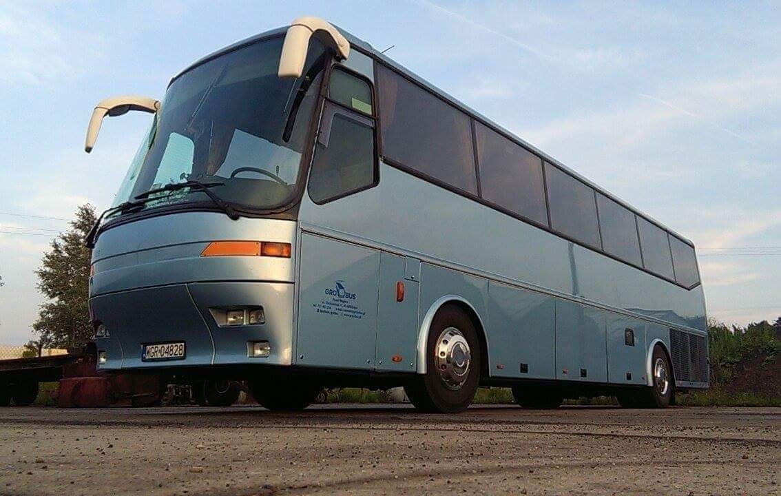 Niebieski autokar BOVA VDL z widocznym logo firmy GRO-BUS i tablicą rejestracyjną na betonowym placu, w tle zieleń.