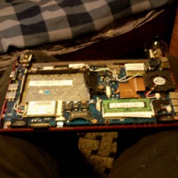 ALL-SERVICE - Wnętrze otwartego laptopa z widoczną płytą główną, elementami chłodzenia i pamięcią RAM. Widoczne ślady naprawy lub konserwacji.