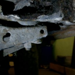 ALL-SERVICE - Nierówna, skorodowana powierzchnia metalowa z otworami i śladami napraw, prawdopodobnie fragment podwozia lub element konstrukcyjny w trakcie renowacji.