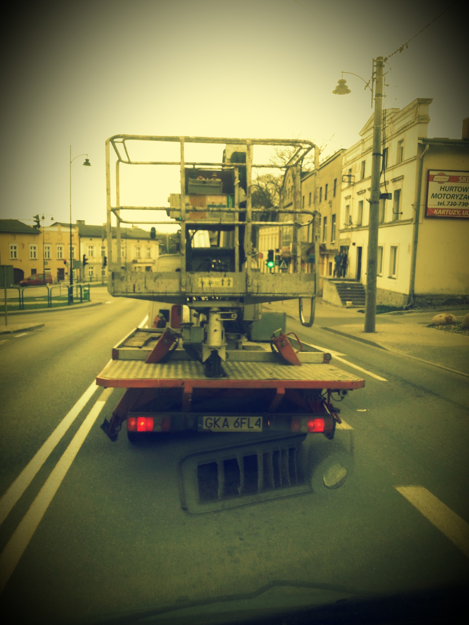 Platforma robocza na lawecie, widok z tyłu na ulicy miejskiej. Tablica rejestracyjna GKA 6FL4. Widoczne budynki w tle i sygnalizacja świetlna.