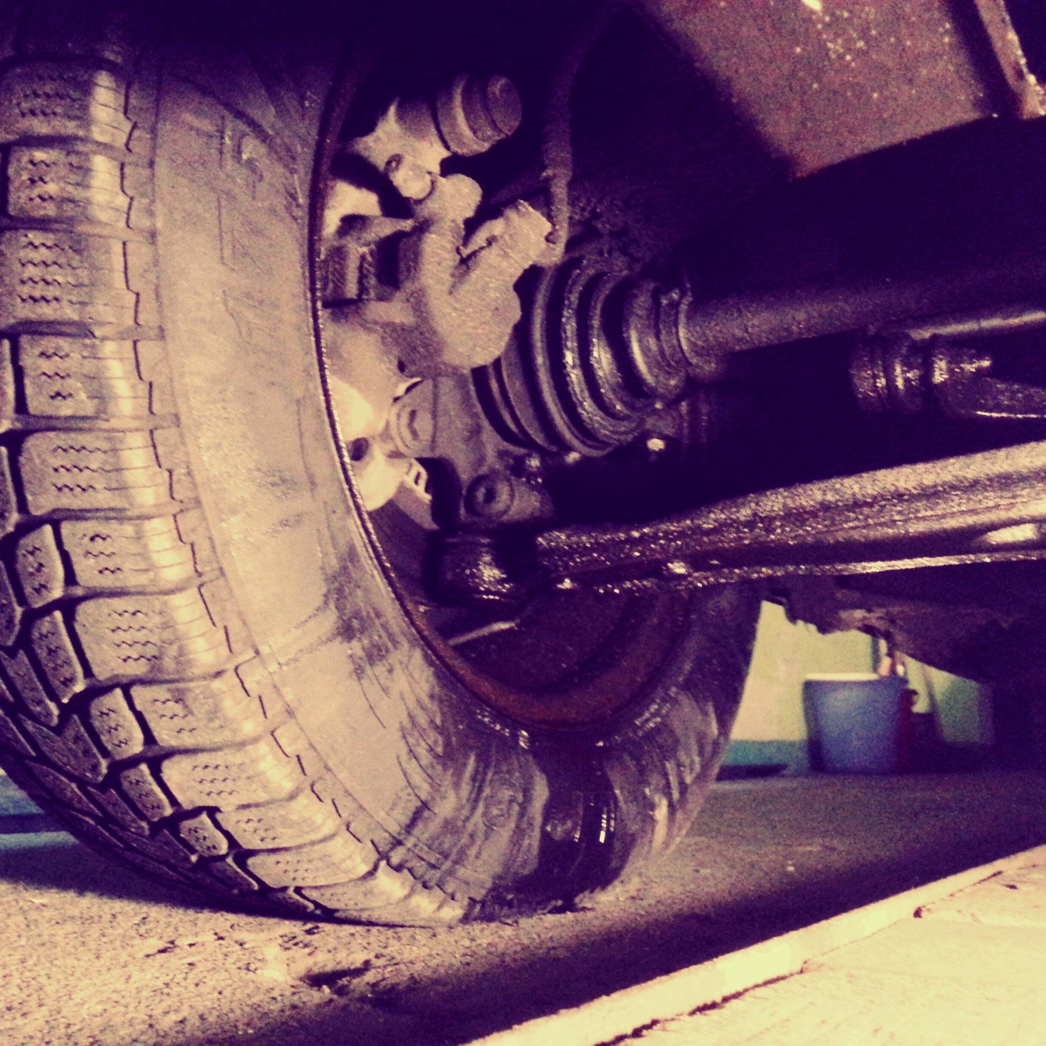 Opona samochodowa z widocznym układem hamulcowym, z bliska, zarys podwozia, prawdopodobnie podczas naprawy.