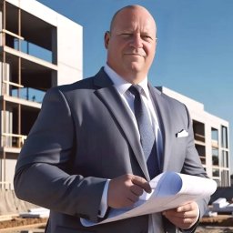 GISA SPÓŁKA Z O.O. - Architekt w szarym garniturze trzymający plany na tle budynku w stanie surowym otwartym, błękitne niebo.