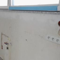 NowakBau - Ściana w trakcie prac przygotowawczych do wykończenia: widoczne instalacje wodne, gniazdka elektryczne, ślady po szpachlowaniu i prowizoryczne oznaczenia na ścianie.