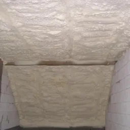 Poddasze ocieplone pianką poliuretanową, widoczne bloki betonowe i drewniana belka konstrukcyjna.