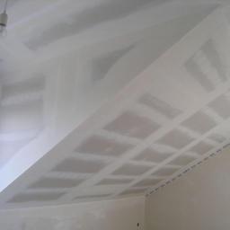 As-Max - Sufit poddasza z zamontowaną płytą kartonowo-gipsową, z widoczną konstrukcją nośną i szpachlowaniem łączeń, zabezpieczony taśmą malarską przy ścianach.