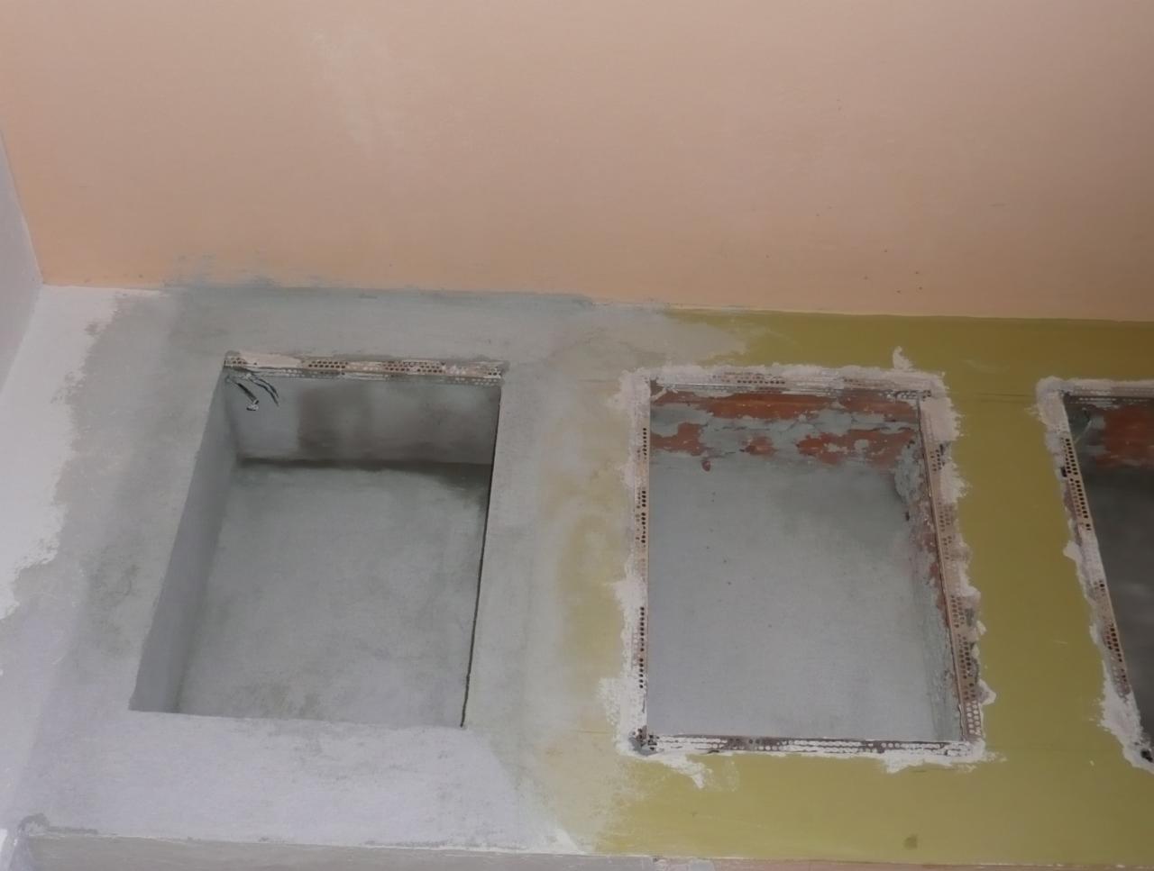 Przygotowanie wnęk w ścianie do zabudowy, widoczne profile i wstępne tynkowanie, fragment instalacji elektrycznej w jednej z wnęk.