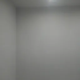 Pusta, świeżo pomalowana szara ściana w rogu pomieszczenia, oświetlona pojedynczym, jasnym punktowym światłem sufitowym.