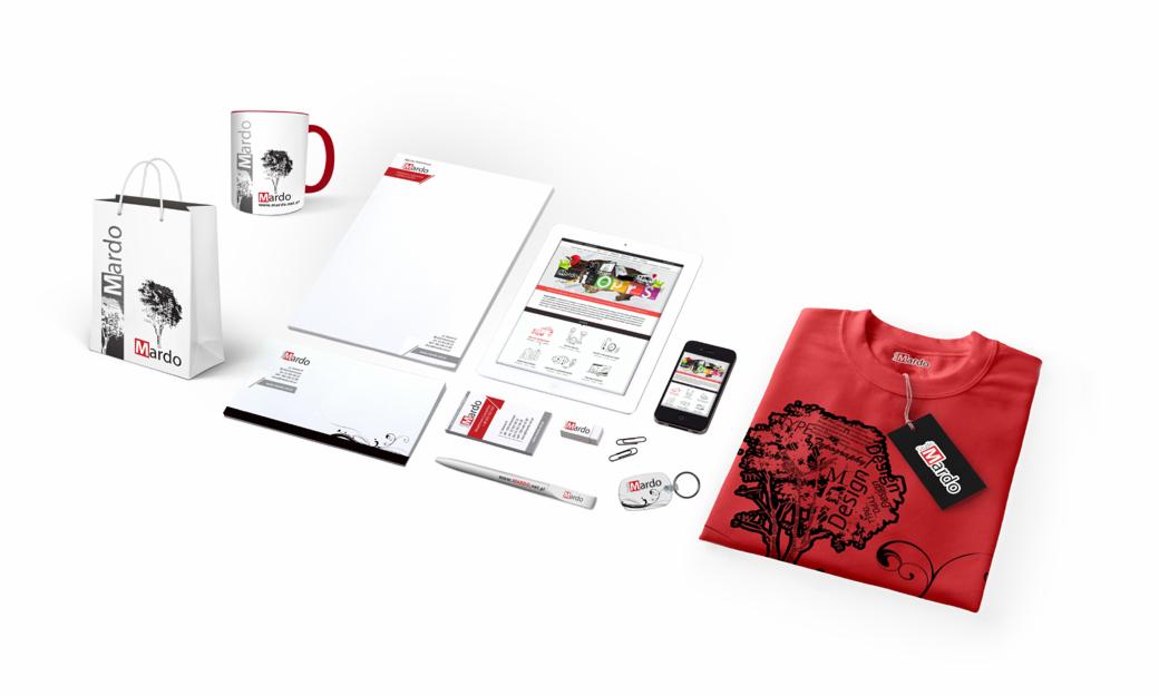 Zestaw artykułów promocyjnych firmy Mardo: koszulka z grafiką, kubek, torba papierowa, wizytówki, długopis, notes, tablet, telefon i inne gadżety z logo firmy, ułożone na białym tle.