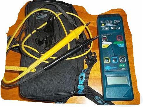 Miernik MIC-3 z przewodami pomiarowymi, leżący na czarnej torbie narzędziowej na tle drewnianego blatu.