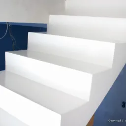 Białe schody z połyskiem, widoczne od dołu, na tle niebieskiej ściany z niedokończonymi pracami elektrycznymi.