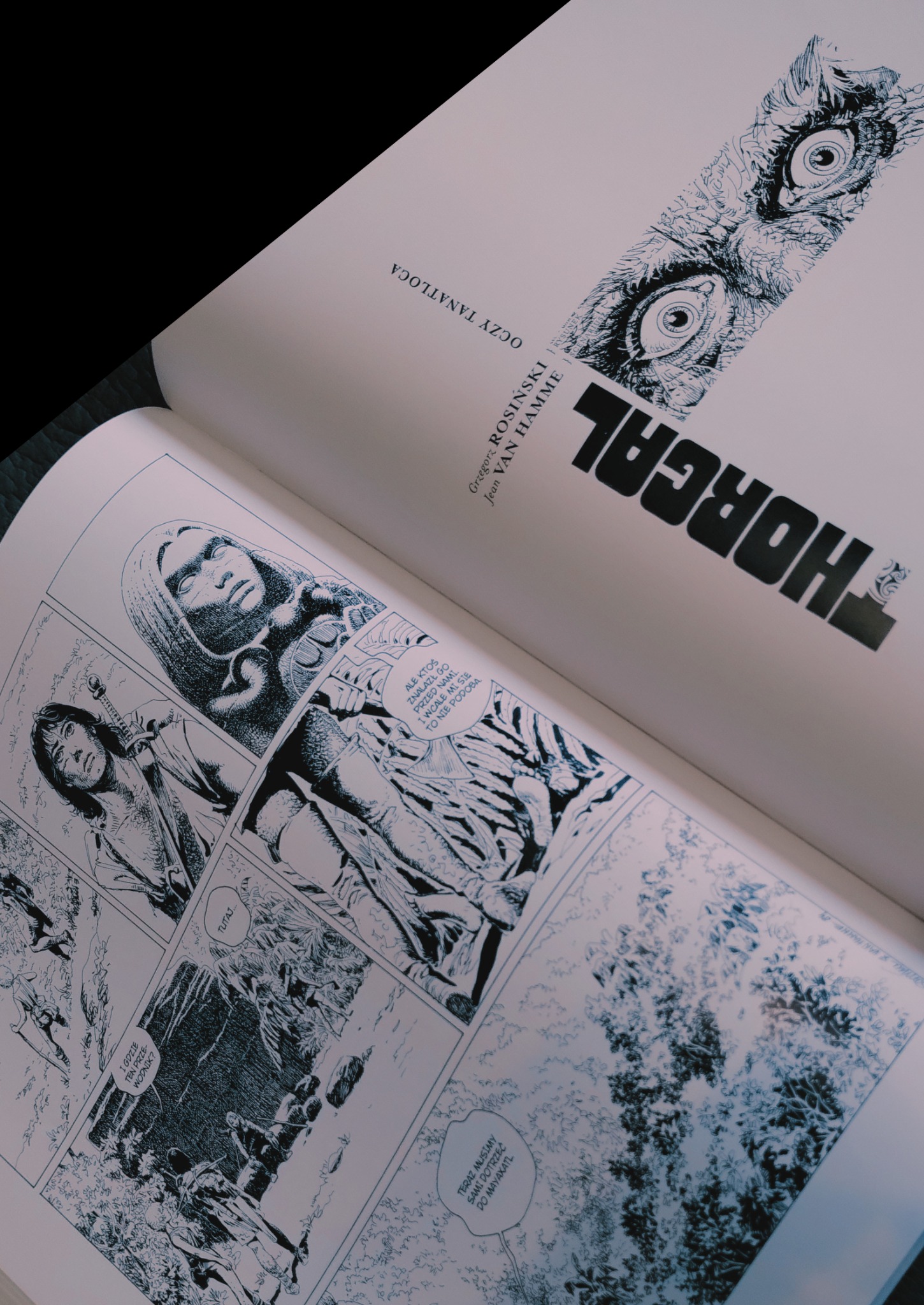 Otwarta książka z komiksem fantasy Thorgal, prezentująca czarno-białe ilustracje i dymki z dialogami. Na stronie widoczne sceny z postaciami w leśnym otoczeniu oraz tytuł i autorzy.