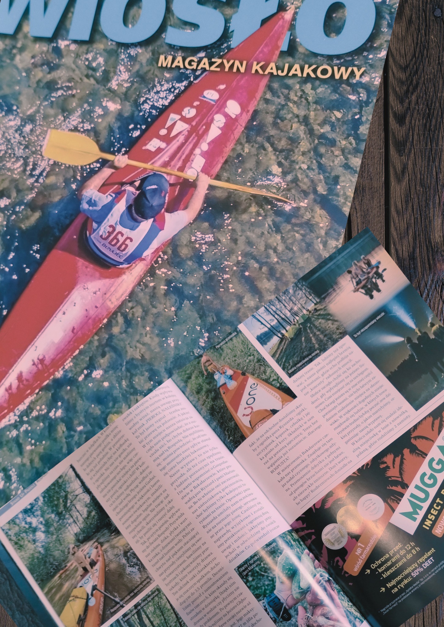 Okładka magazynu kajakowego 'Wiosło' z kajakarzem na wodzie i otwarte strony z artykułami o spływach kajakowych, leżące na drewnianym stole.