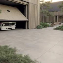 Nowoczesna nawierzchnia z dużych, szarych płyt na podjeździe, z garażem z drewnianą bramą i białym samochodem w tle, otoczona zielenią.