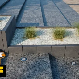 Szara nawierzchnia z kamienia naturalnego z wbudowanymi lampami oświetleniowymi i rabatami z białym grysem oraz trawami ozdobnymi, widoczny fragment logo producenta.