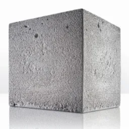 Betonowy sześcian o porowatej powierzchni, widoczne małe wgłębienia i refleksy świetlne na gładkiej powierzchni podłoża.