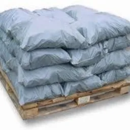 Stos worków ułożonych na drewnianej palecie, widoczne lekkie zagniecenia na workach, sugerujące ich wypełnienie.