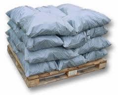 Stos worków ułożonych na drewnianej palecie, widoczne lekkie zagniecenia na workach, sugerujące ich wypełnienie.