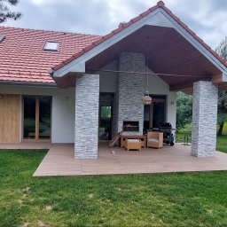 Eco Sense Sp. z o.o. - Nowoczesny dom z tarasem w Dzierżoniowie. Elewacja z kamienia dekoracyjnego, czerwona dachówka i jasne ściany. Grill i meble ogrodowe na tarasie.