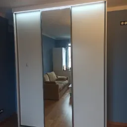 Zabudowa wolnostojąca z drzwiami przesuwnymi, lustrem i oświetleniem ledowym.